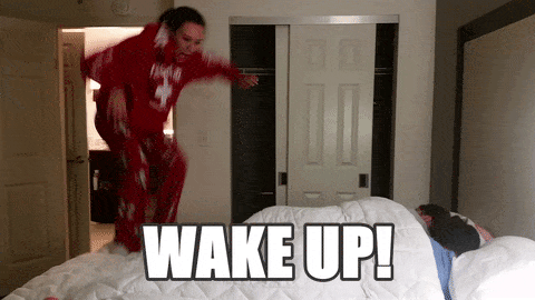 woman jumping on bed saying wake up