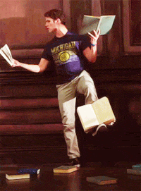 man holding books while balancing a book on his foot