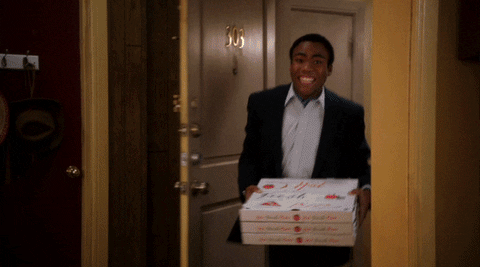 a man holding pizza into a room on fire gif