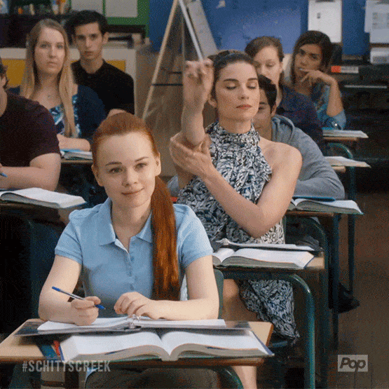 Alexis Rose raising her hand in class