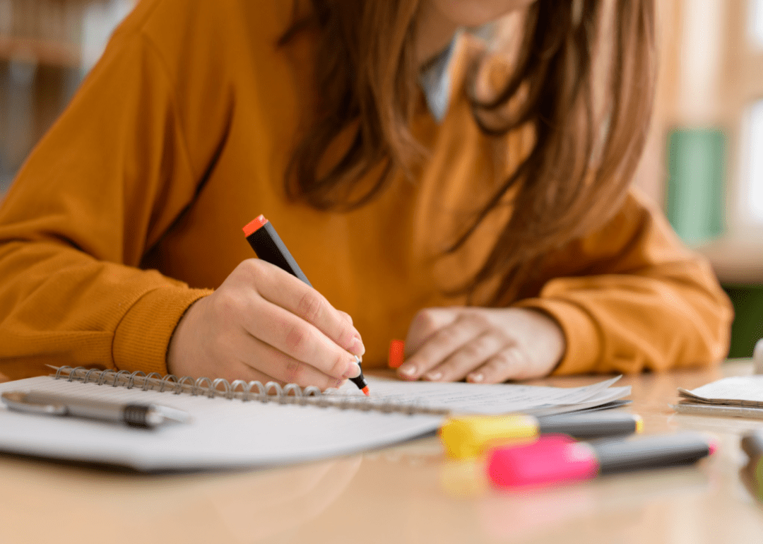 A woman using a highlighter to highlight notes 