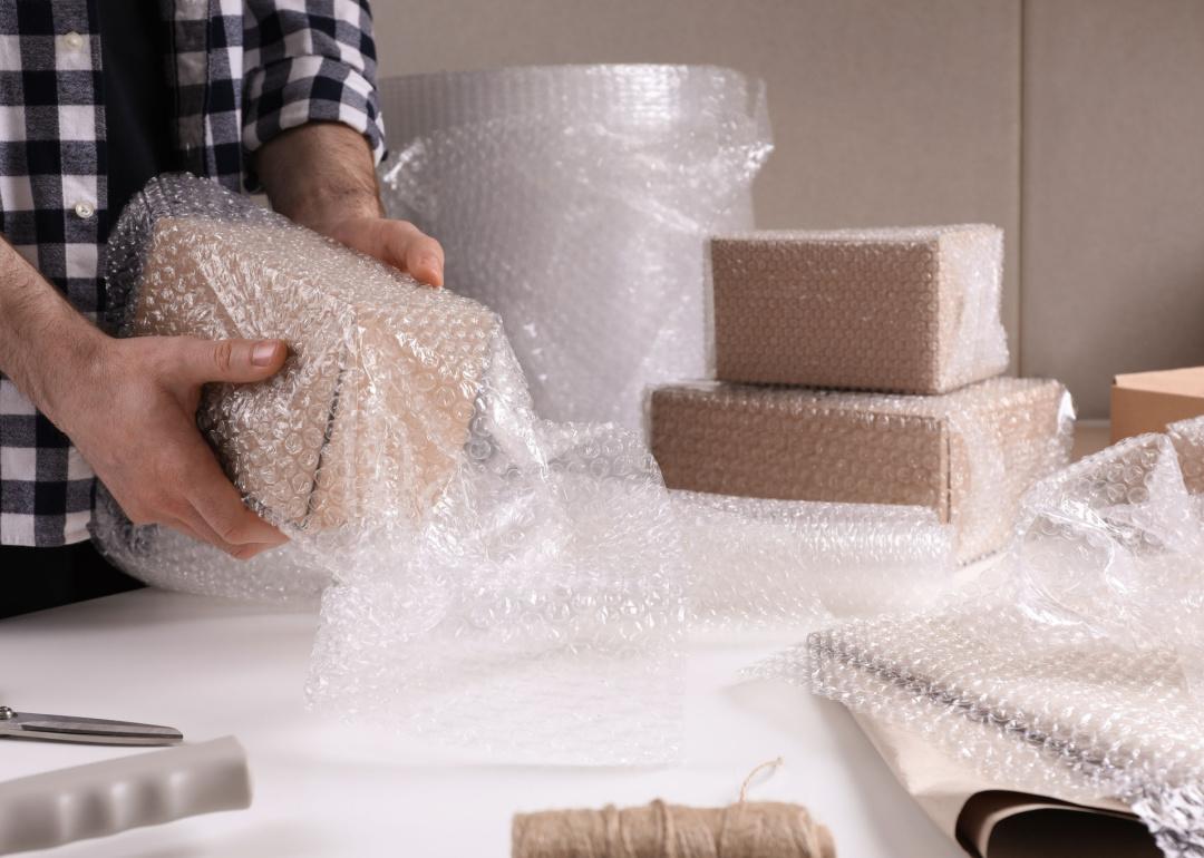 A person wrapping a box with bubble wrap