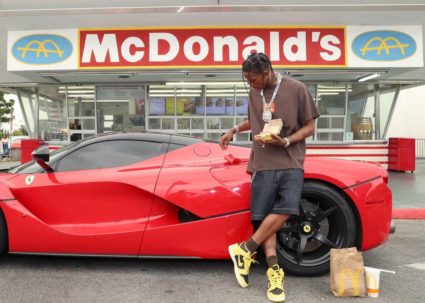 Travis Scott in front of a red car and McDonald's