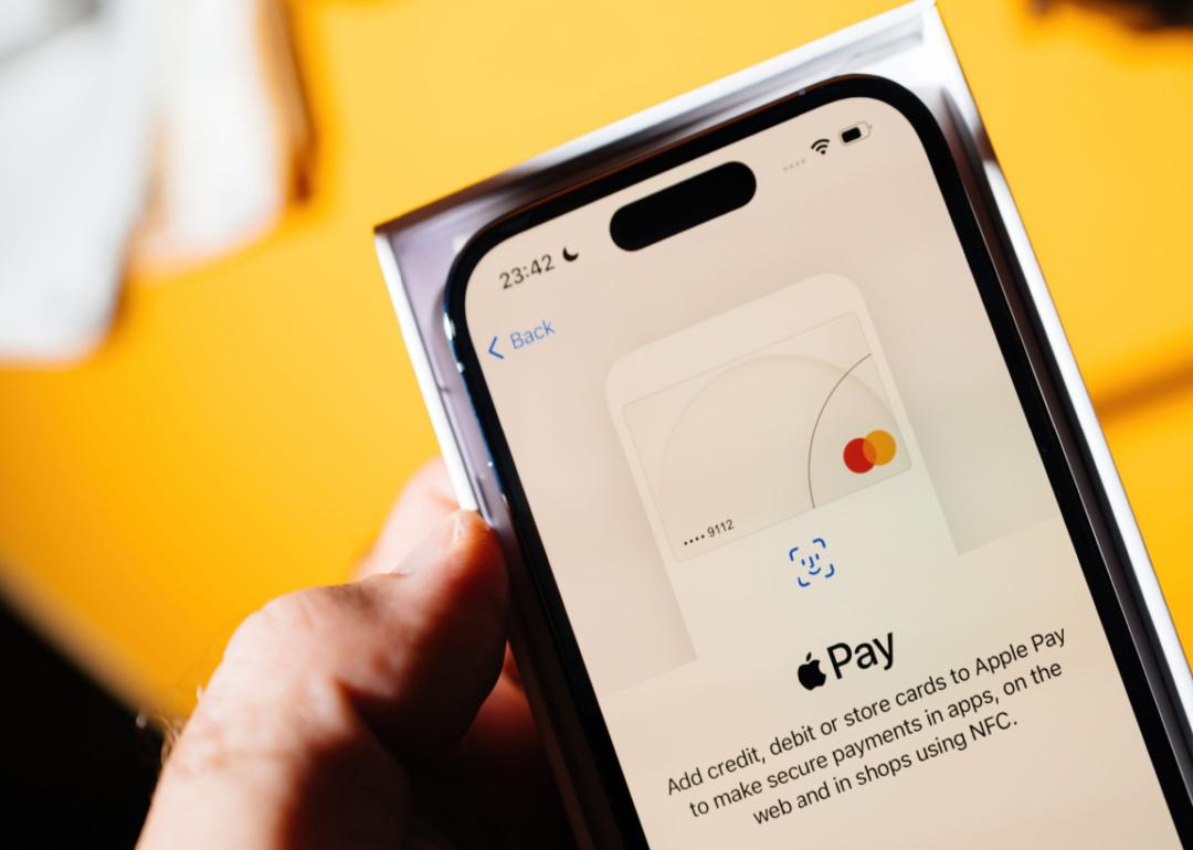 A person holding an iPhone with Apple Pay on the screen