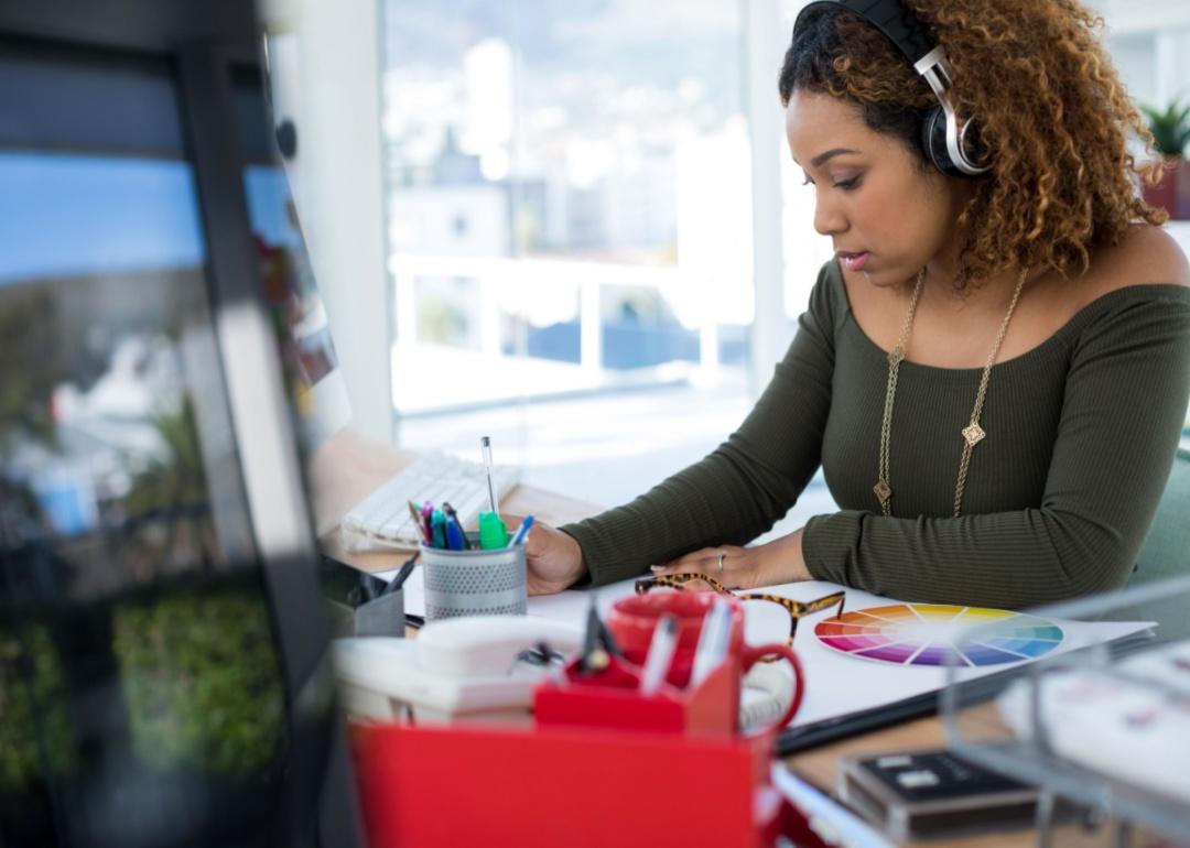 Een vrouw werkt aan een ontwerp met een koptelefoon op