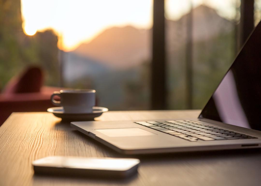 Laptop, Telefon und ein Kaffeebecher auf einem Tisch