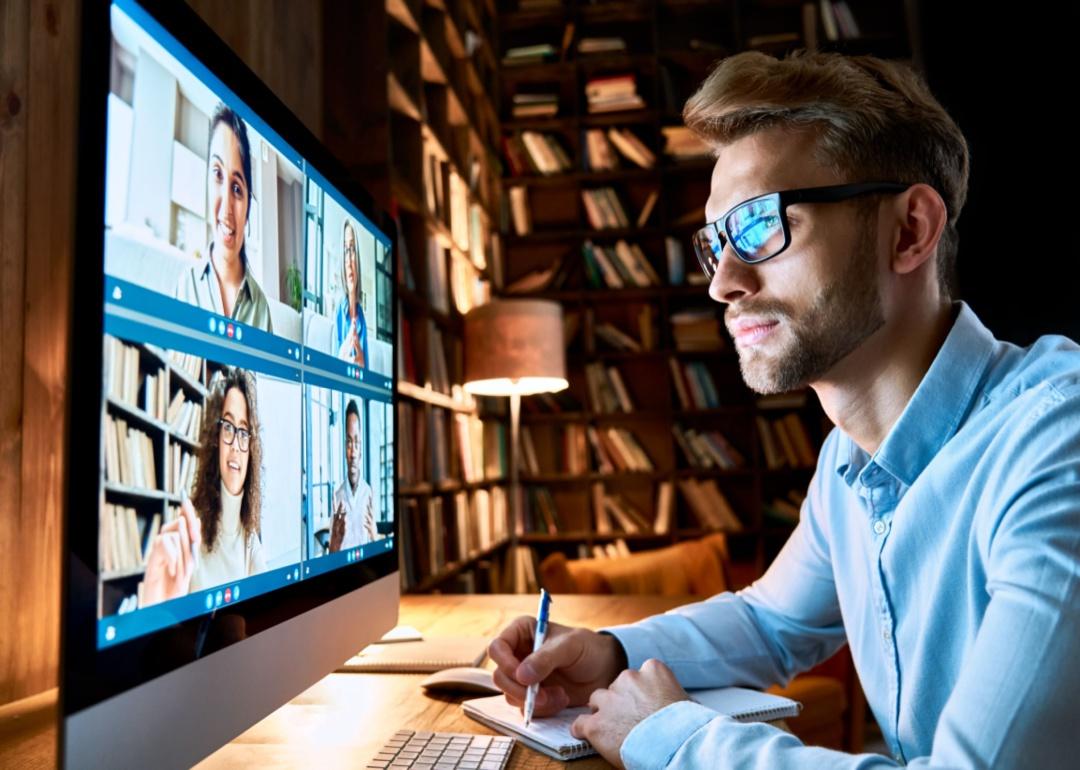 Um homem de óculos colaborando com outras pessoas por meio de videoconferência