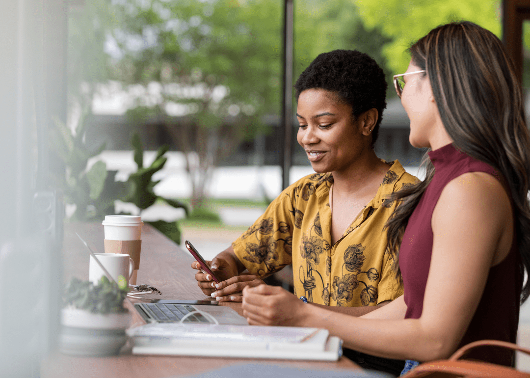 Due donne che lavorano insieme al loro computer portatile e allo smartphone