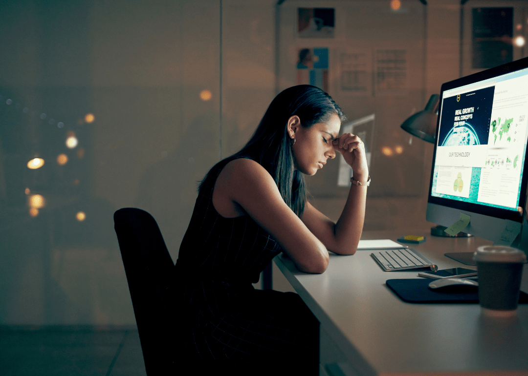 A woman looking tired and stressed in front of a computer 