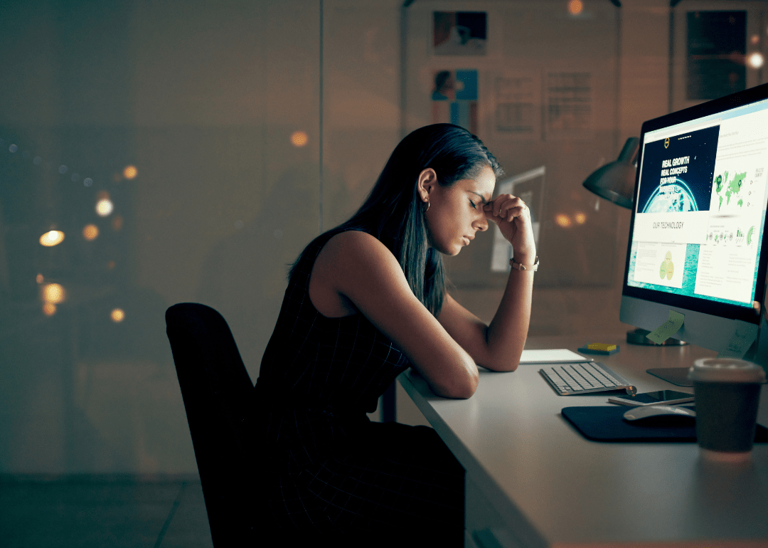 Uma mulher parecendo cansada e estressada na frente de um computador