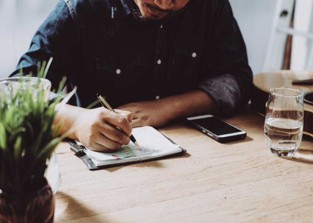 A man writing in a notebook with a pen