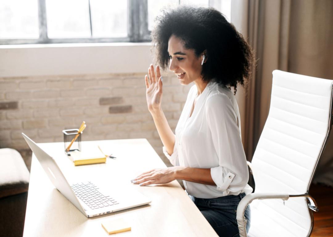 A woman waving at her laptop 