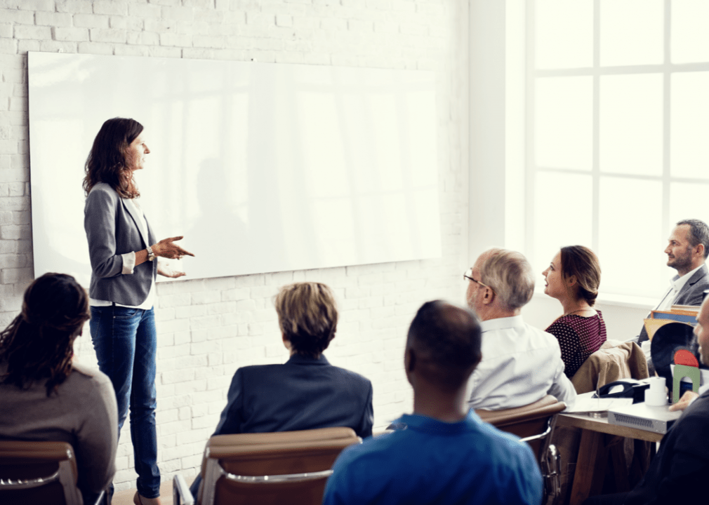 Una mujer presenta en una reunión delante de la gente