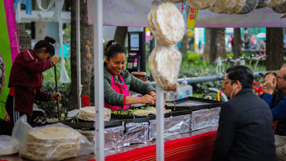 Image of a woman cooking in a street food stall while a man watches